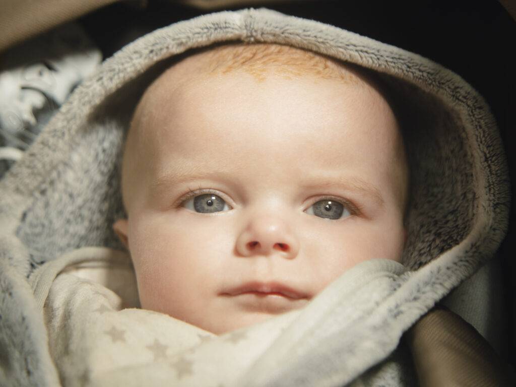 photo de maternité d'un enfant gros plan avec des yeux clair et avec une capuche