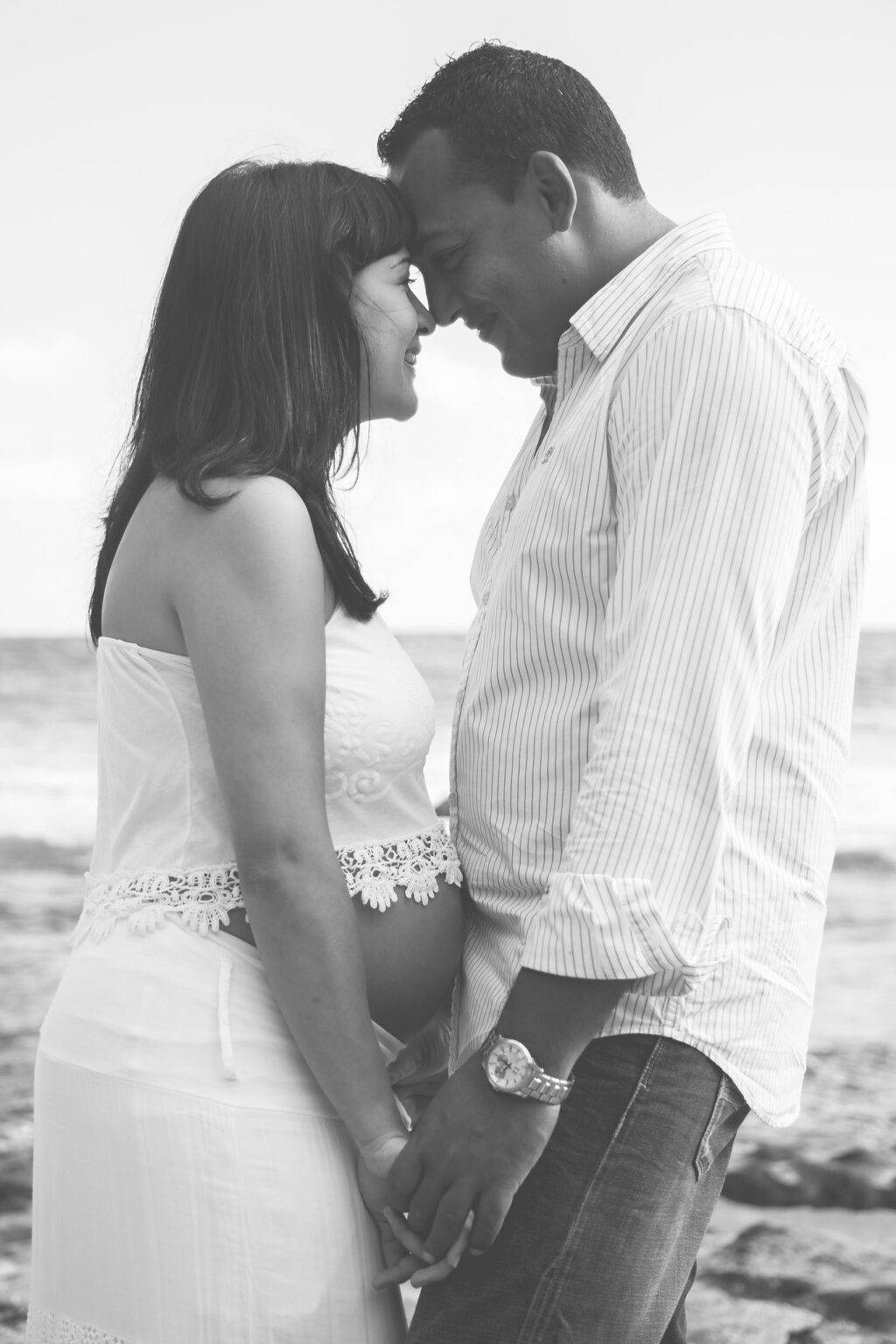 photo de maternité d'un couple tout habillé souriant se tenant face à face