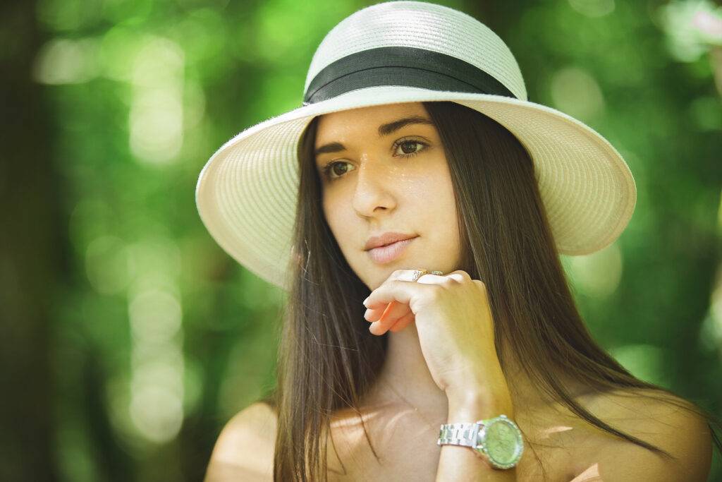 portrait de jeune femme avec un chapeau sur fond naturel vert