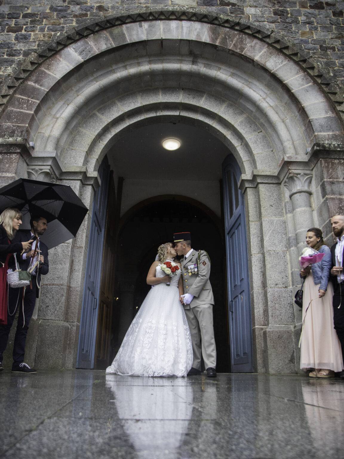 photo de mariage couple sous l'arche d'une porte d'église